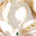 Pear-shaped green CZ halo pendant necklace, flat lay